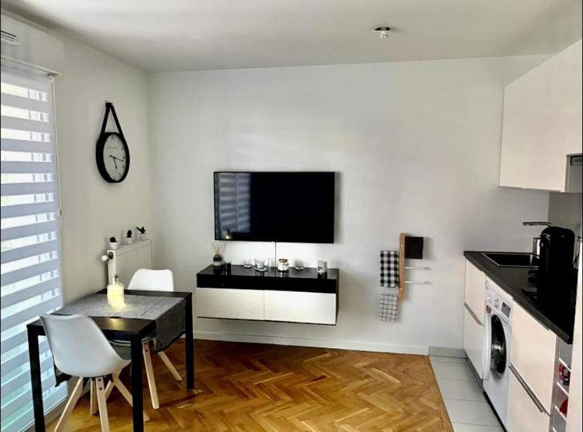 a kitchen with a table and a tv on a wall at Superbe studio lumineux haut de gamme tout confort in Drancy