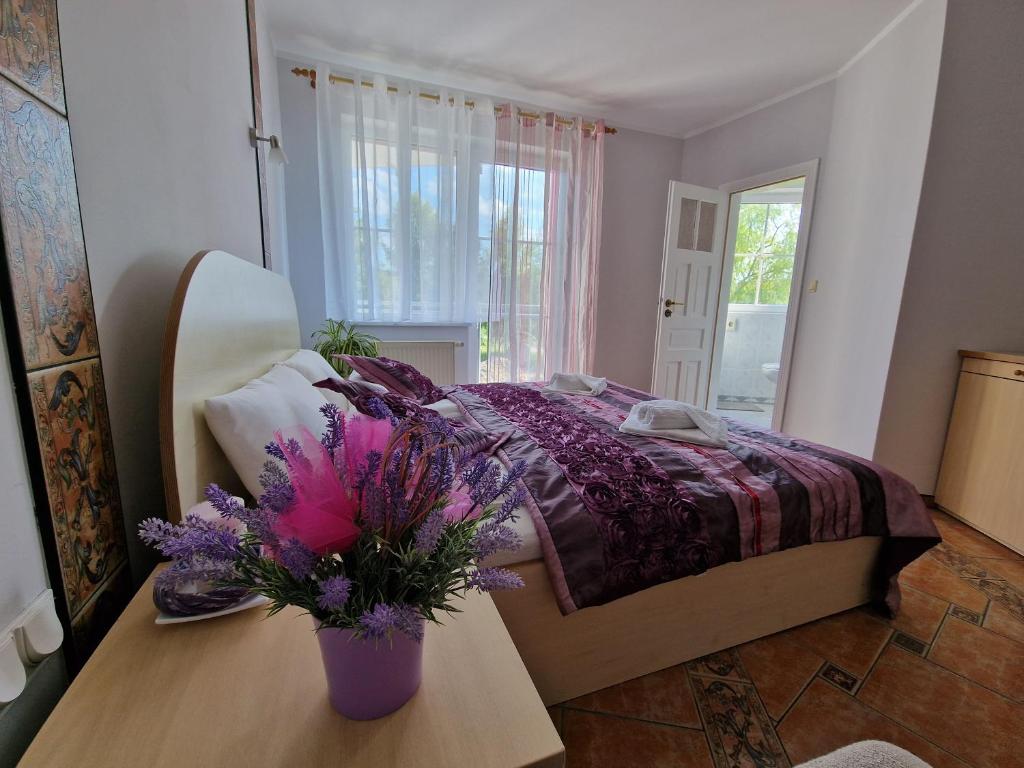 um quarto com uma cama e um vaso de flores sobre uma mesa em Apartament Hexagon nr 14 em Grzybowo