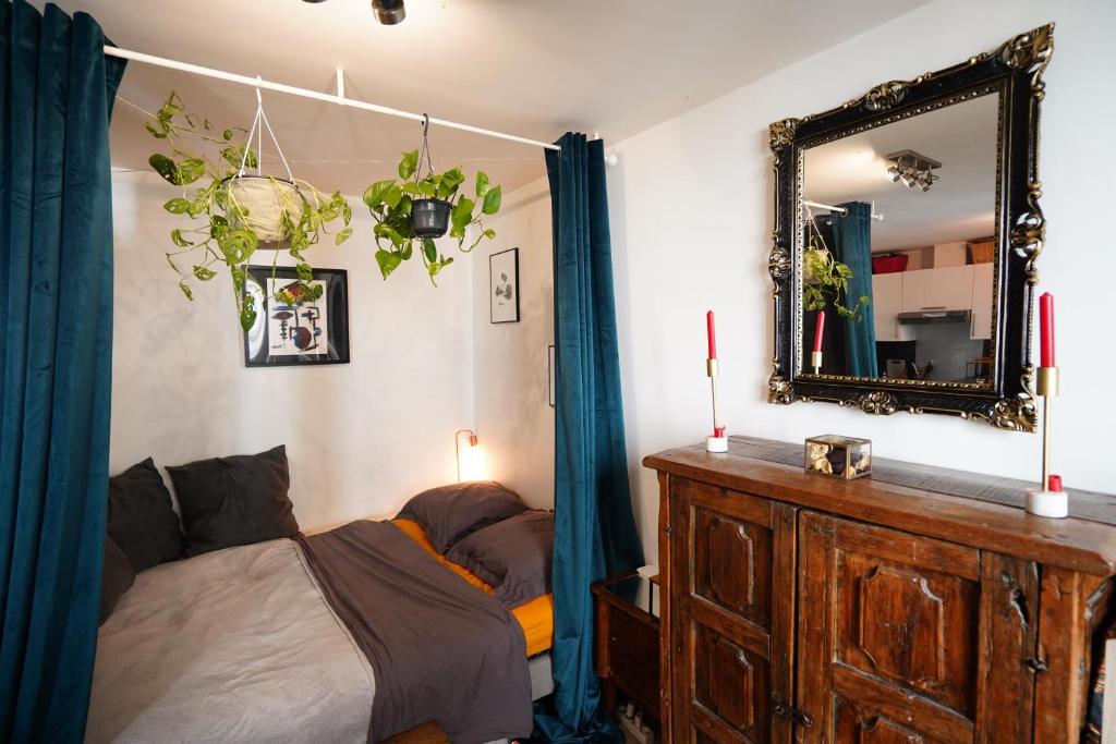 - une chambre avec un lit, un miroir et une commode dans l'établissement Charmant studio au calme et bien desservi, à Paris
