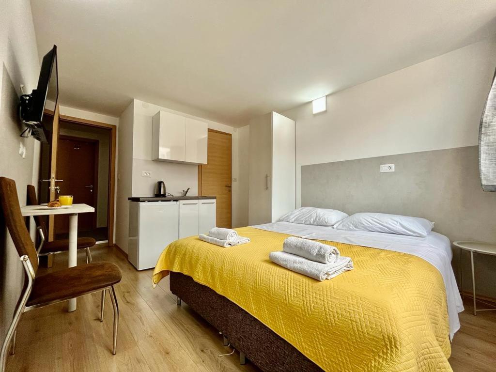 a bedroom with a yellow bed with towels on it at Apartmani ROZA in Pula