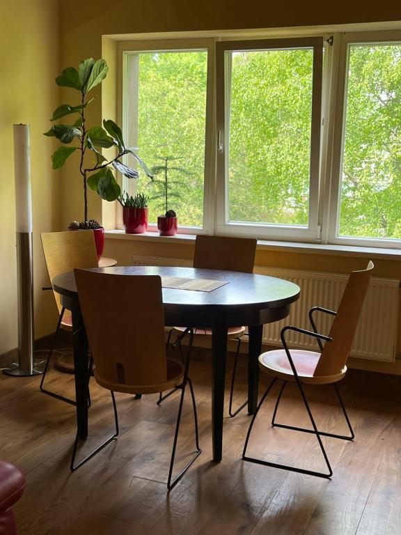 une table et des chaises dans une pièce avec fenêtres dans l'établissement Apartamentai Palangos Centre, à Palanga