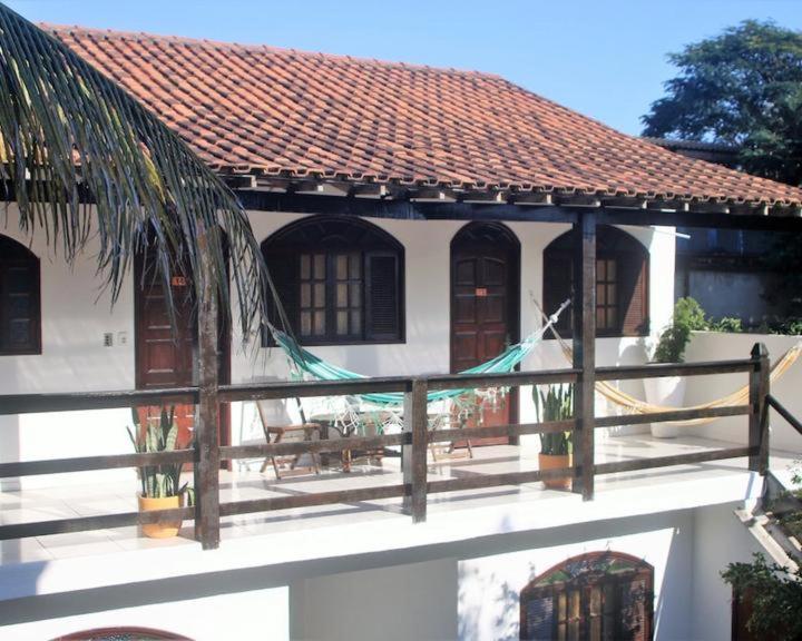Casa blanca con techo y valla de madera en Pousada Porto Búzios, en Búzios