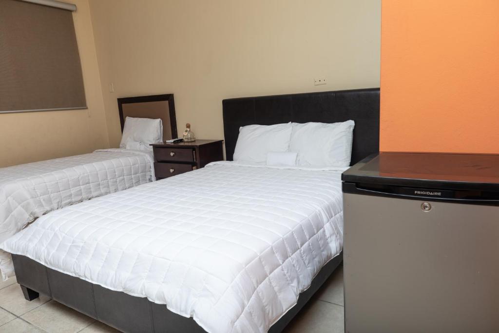 una camera d'albergo con due letti con lenzuola bianche di Red Sunset Beach Club a Boquerón