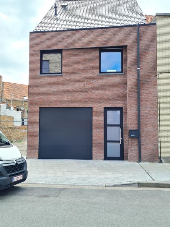 una casa de ladrillo con un garaje con un coche aparcado delante en Vakantiehuis Mariakerke, en Ostende