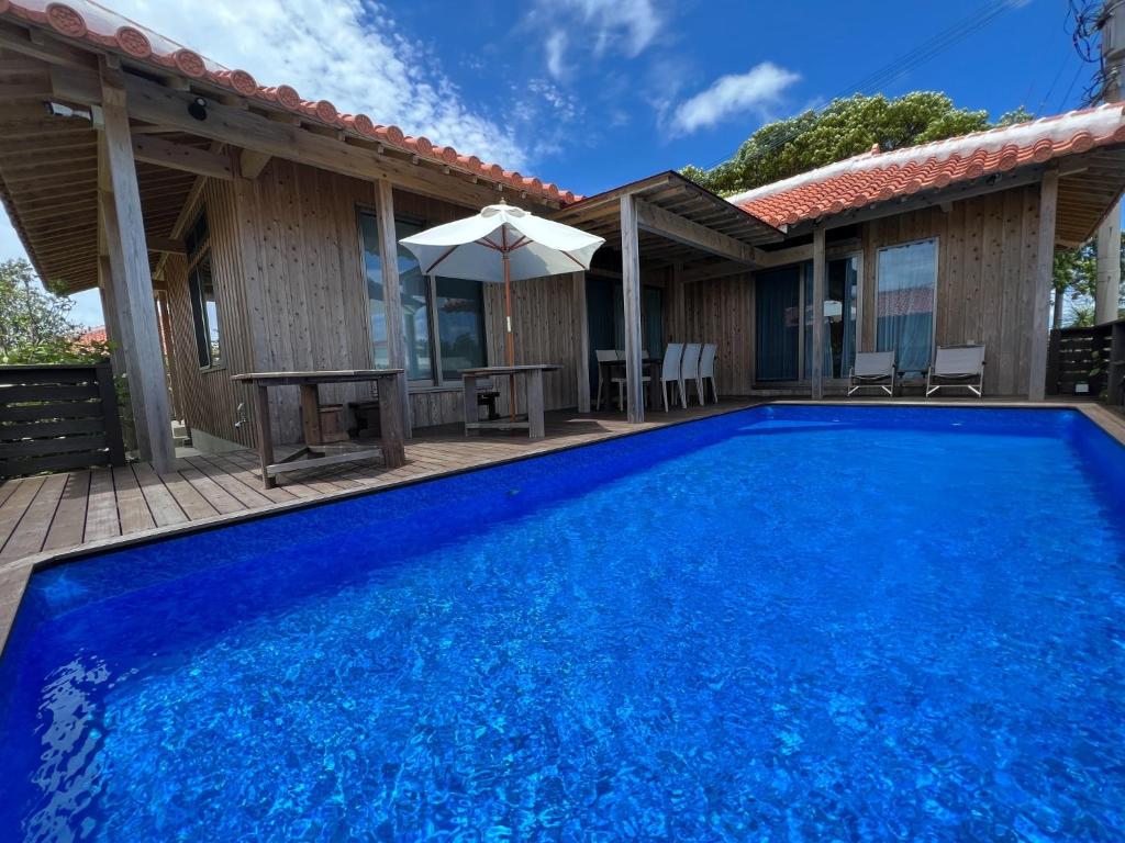 een blauw zwembad met een tafel en een parasol bij The Villa with a YAMAHA C6X - Villa Muse Okinawa- Vacation STAY 43827v in Nago