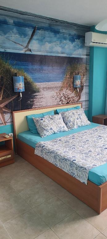 a bed in a room with a painting of a beach at Guest House Chalakov in Sinemorets
