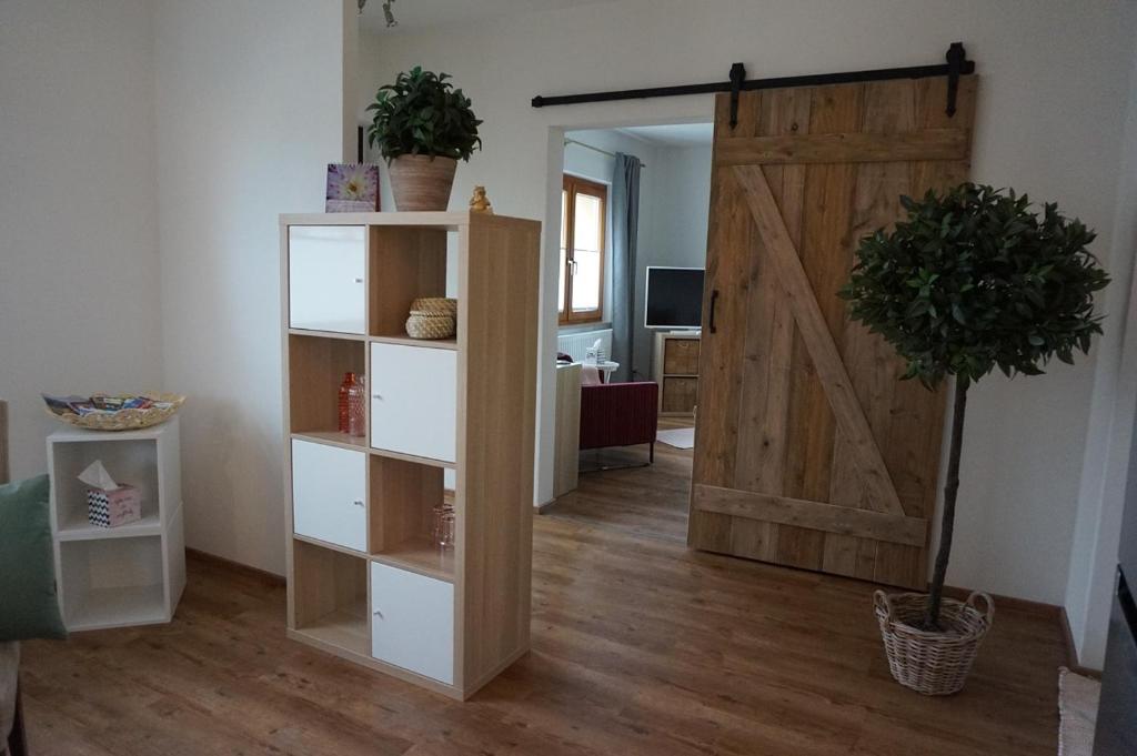 una sala de estar con una puerta de madera y una habitación en Casa Maria, en Amtzell