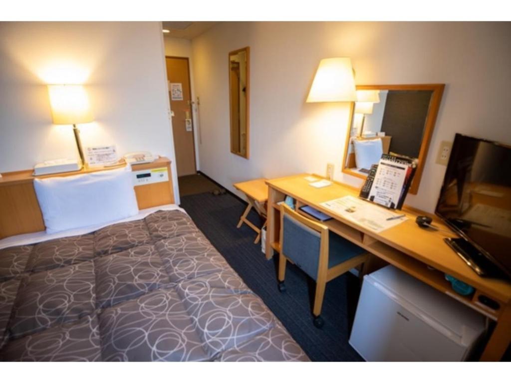 半田市にあるAZ INN HANDA INTER - Vacation STAY 69370vのベッド、デスク、コンピュータが備わるホテルルームです。