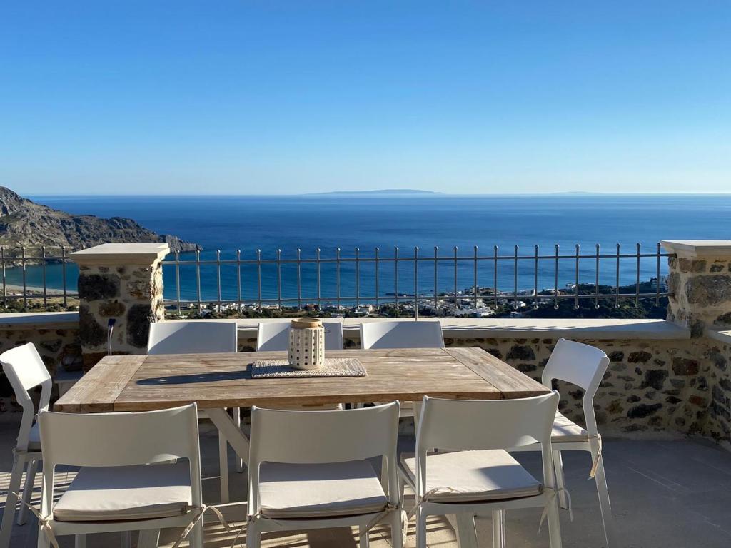 a wooden table and chairs on a balcony with the ocean at Meraki Apartments Crete in Plakias
