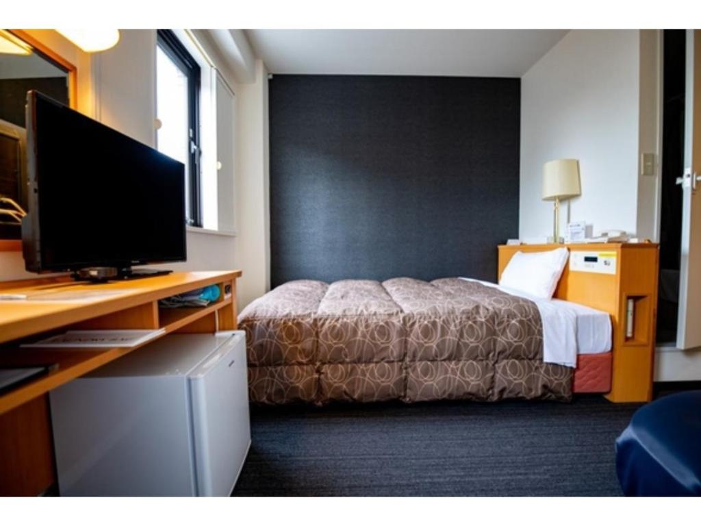 um quarto de hotel com uma cama e uma secretária com uma televisão em AZ INN HANDA INTER - Vacation STAY 69374v em Handa