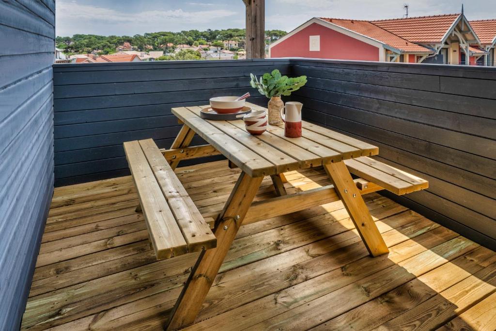 drewniany stół i ławka na tarasie na dachu w obiekcie Mamita1"Apartment delight of the pines"spacious bright T3 62m18mterrace w mieście Lacanau
