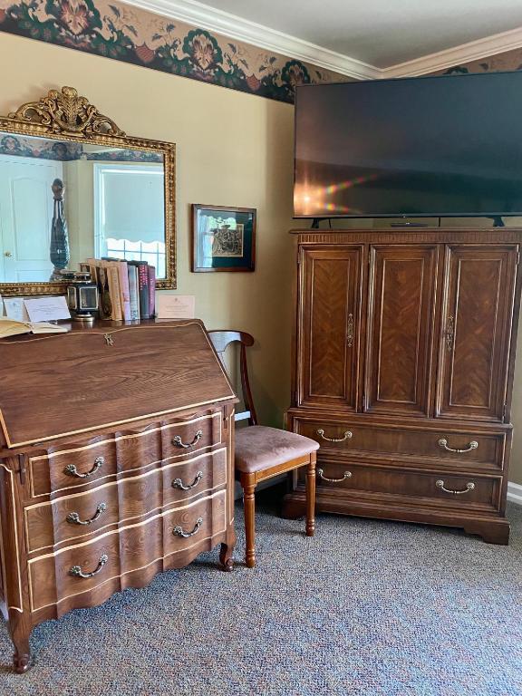 a bedroom with a dresser and a large television at The Cypress Inn in Conway