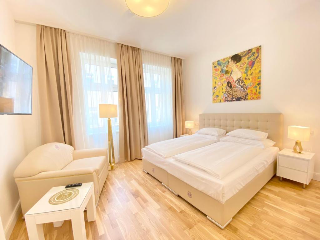 um quarto com uma grande cama branca e uma cadeira em Steiner Residences Vienna Nestroyplatz em Viena