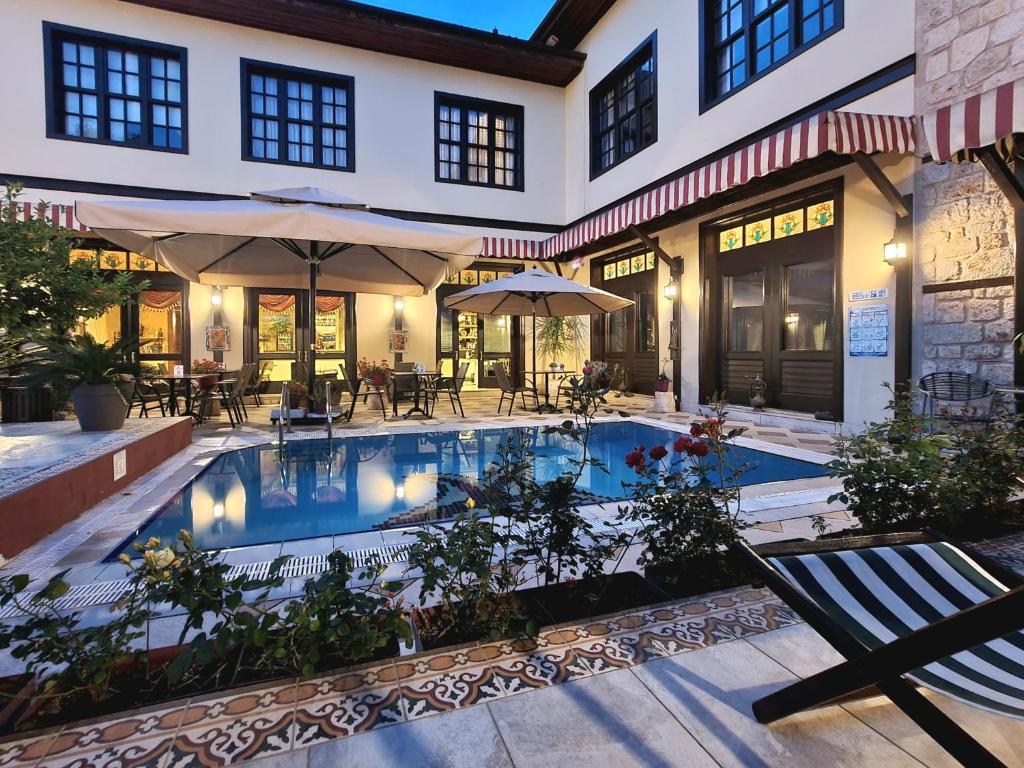 a swimming pool with tables and umbrellas next to a building at Eski Masal Hotel - Special Class in Antalya