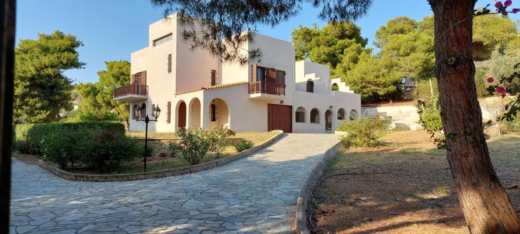 un gran edificio blanco con un árbol delante en Casadelvilla private apartment PortoCheli-Kosta en Porto Heli