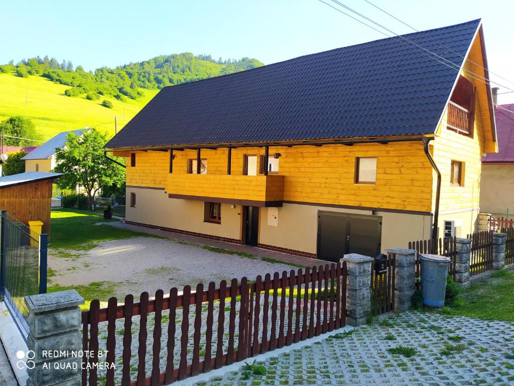 ein Haus mit einem schwarzen Dach mit einem Zaun in der Unterkunft Chalupa Praženica in Liptovské Revúce