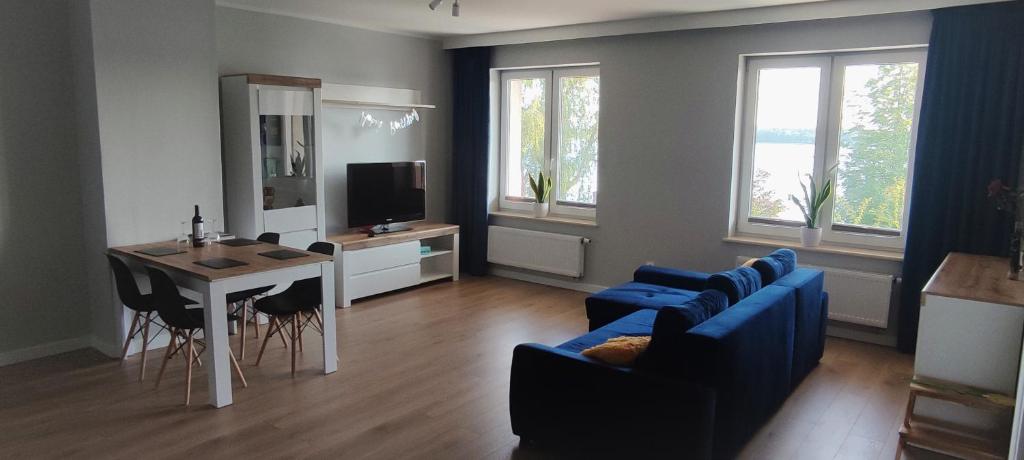 a living room with a blue couch and a table at Apartamenty Przystań in Ełk