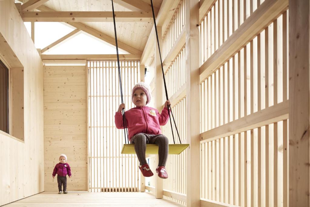 Ein kleines Mädchen sitzt auf einer Schaukel in einem Gebäude in der Unterkunft Ferienhaus Islen in Mellau