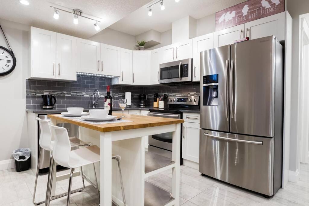 a kitchen with white cabinets and a stainless steel refrigerator at Stunning 2 BDRM YEG Suite, EIA Airport, WiFi! in Edmonton
