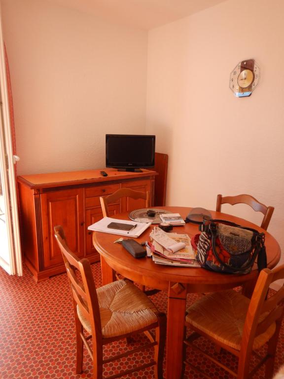 Pokój z drewnianym stołem z krzesłami i telewizorem w obiekcie Appartement 4 personnes - Argelès-sur-Mer w Argelès-sur-Mer