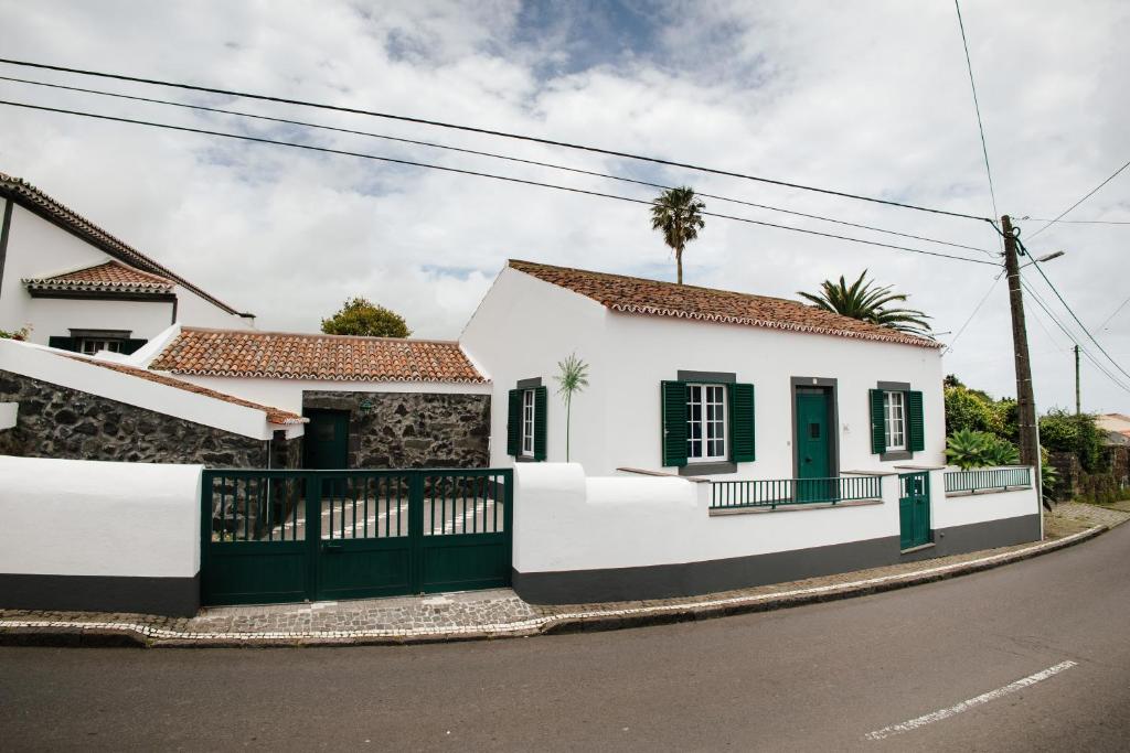 Biały dom z zielonymi drzwiami na ulicy w obiekcie Casa das Palmeiras w mieście São Vicente Ferreira