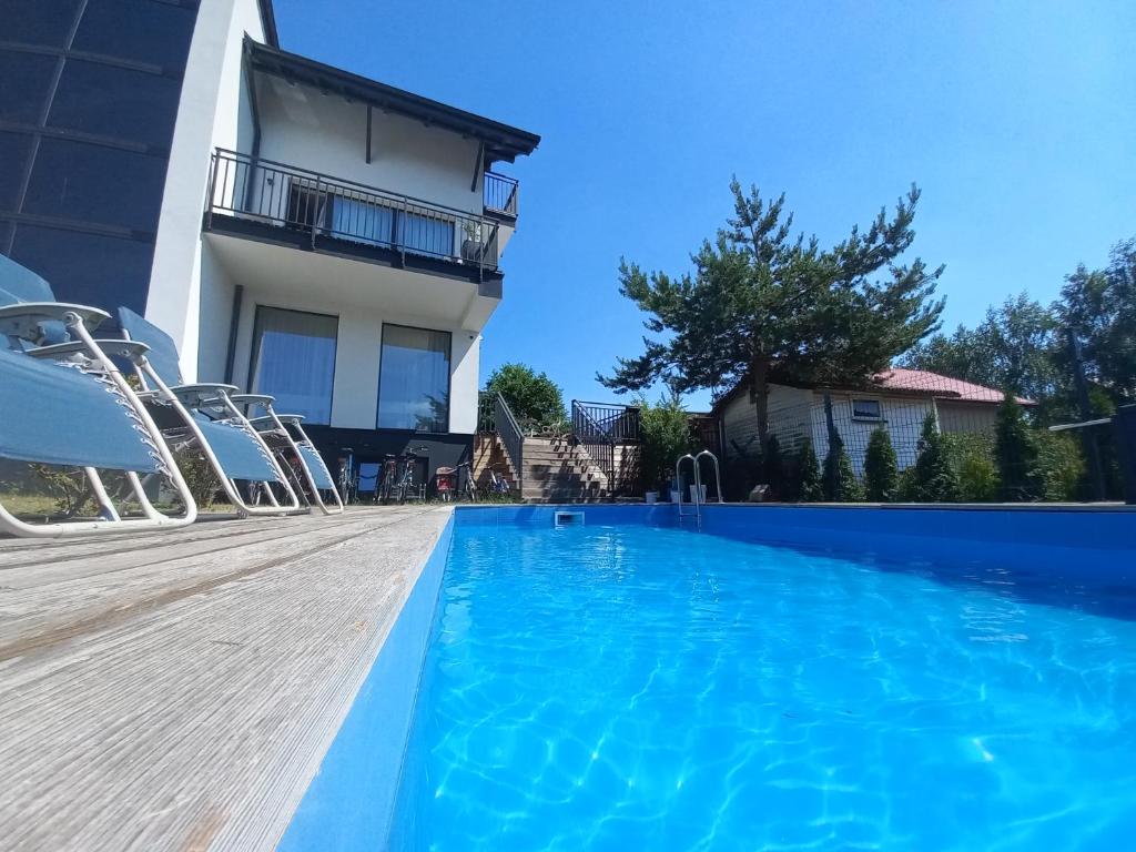 a swimming pool with chairs in front of a building at Azymut in Jarosławiec