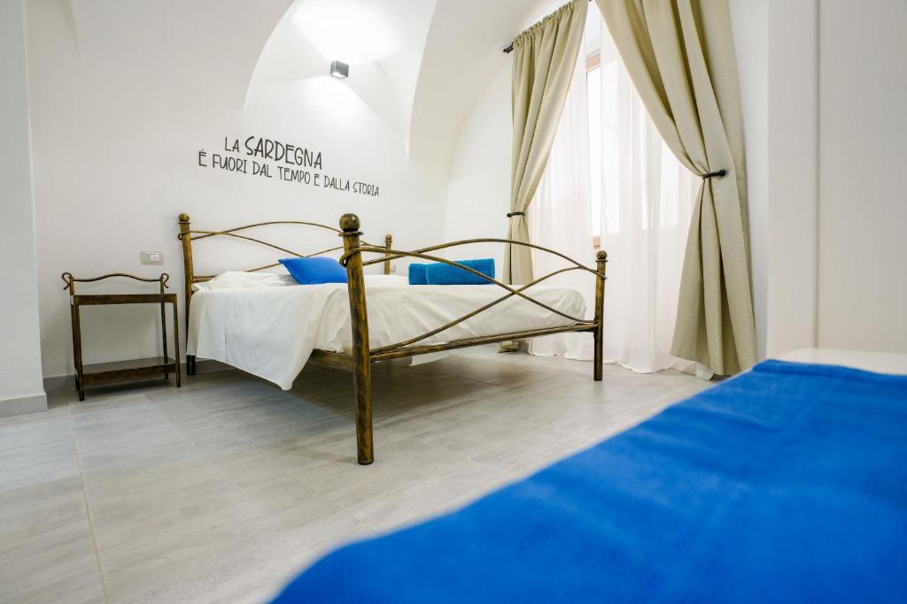 a bedroom with a bed with blue sheets and a window at Casa Mirto in Bosa