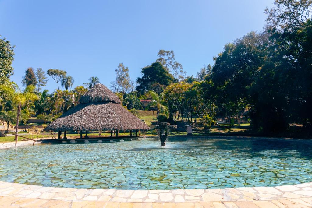 uma fonte numa piscina de água com uma cabana de palha em Rio Quente Resorts - Eco Chalés em Rio Quente