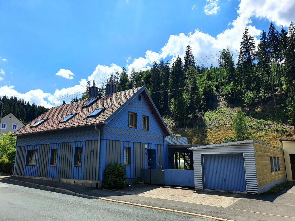 ein blaues Haus mit einer Garage an der Straßenseite in der Unterkunft Ferienwohnung Bei Vogel in Geroldsgrün