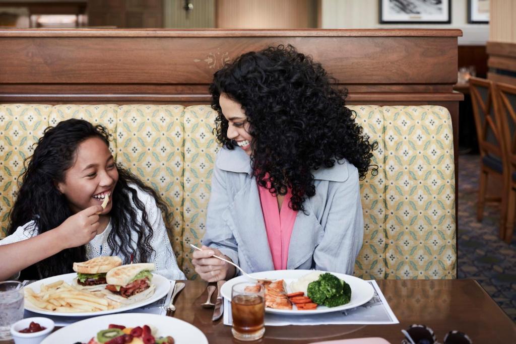two women sitting at a table with plates of food at Little America Hotel Salt Lake City in Salt Lake City