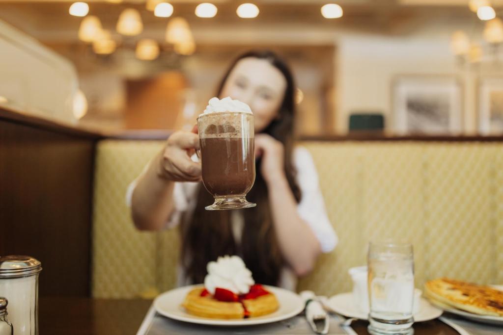 a woman sitting at a table with a drink at Little America Hotel Salt Lake City in Salt Lake City