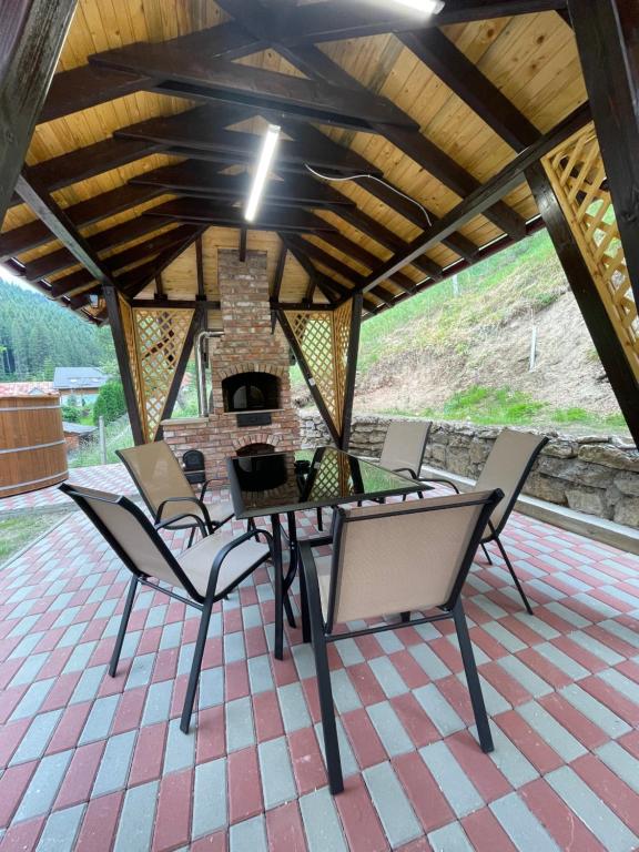 einen Tisch und Stühle auf einer Terrasse mit Kamin in der Unterkunft Casa de vacanță Cheșa in Borsec