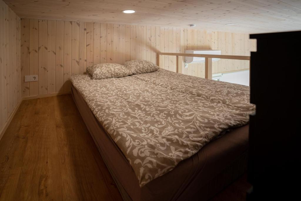a large bed in a room with wooden walls at AITVARU TERASOS apartamentai pirmame aukšte su terasa į kanalą in Svenele