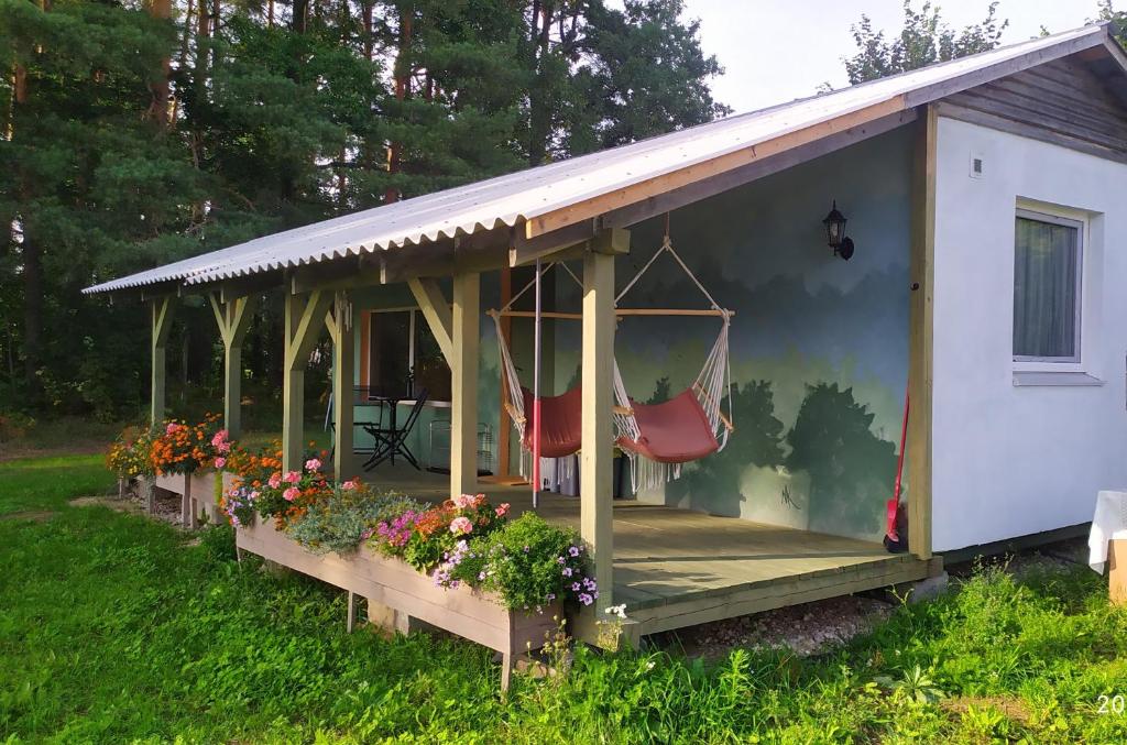 ein Haus mit einer Veranda mit 2 Stühlen und Blumen in der Unterkunft Namiņš Sidrabi pie upes in Koknese