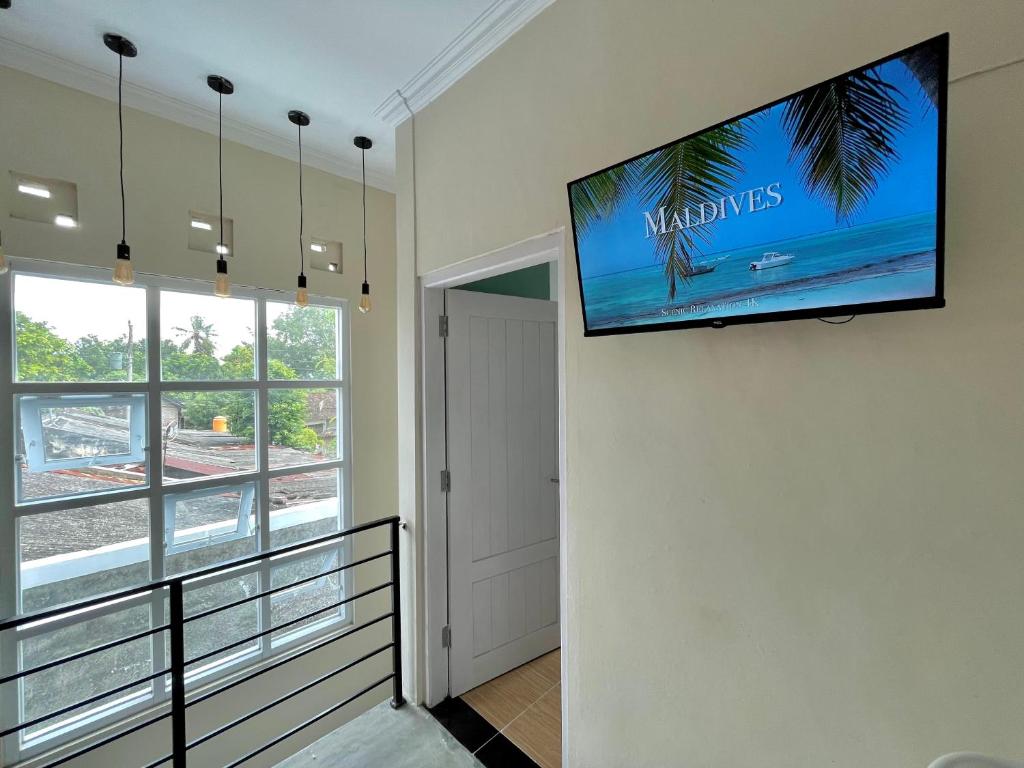 einen Flachbild-TV, der an einer Wand im Flur hängt in der Unterkunft Rumah Paron Homestay Barat in Yogyakarta