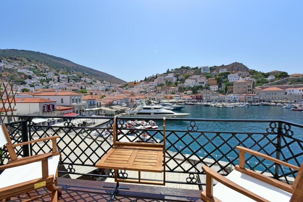 a balcony with two chairs and a view of a harbor at Estia Hydra in Hydra