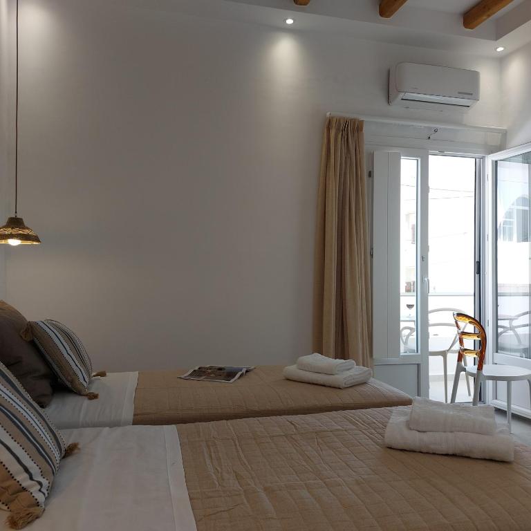a bedroom with two beds and a balcony at Elite Suites Naxos in Naxos Chora