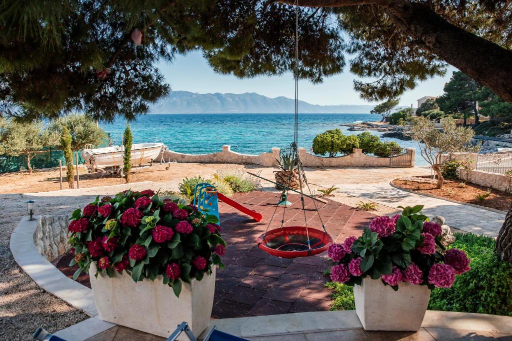 twee bloemen in witte potten op een tafel bij de oceaan bij Villa Danka in Sućuraj