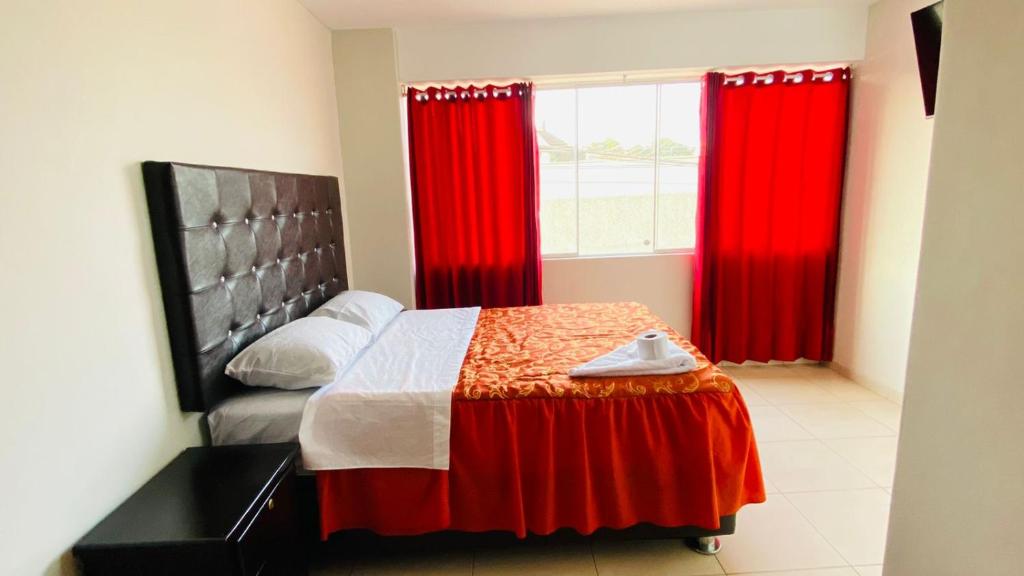 a bedroom with red curtains and a bed with a table at Hospedaje Nápoles in Trujillo