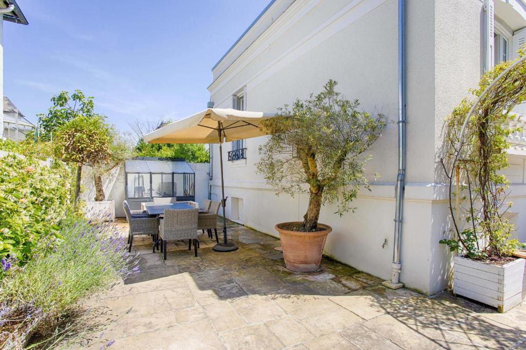 a patio with a table and an umbrella at The White House - Deauville in Deauville