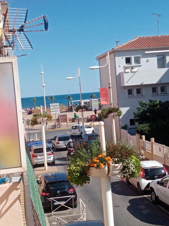 - une vue sur un parking avec des voitures et l'océan dans l'établissement Séjour Valras-Plage T3 Vue sur Mer - 50m centre et mer, à Valras-Plage