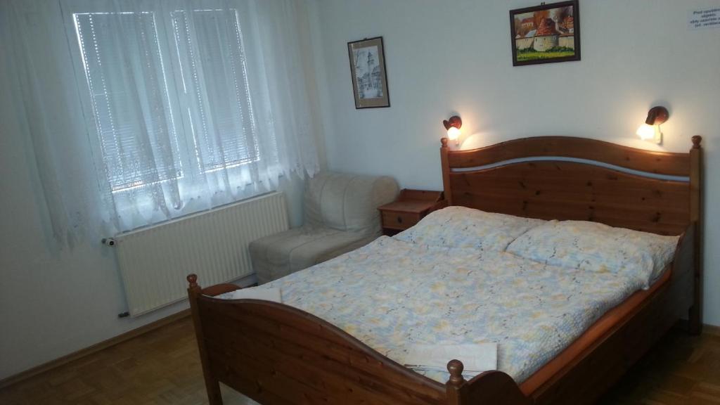 トレボンにあるPenzion Chocholoušekのベッドルーム(木製ベッド1台、椅子付)