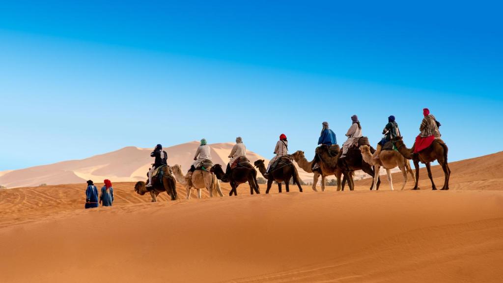 a group of people riding horses in the desert at Sultan Luxury Camp in Merzouga