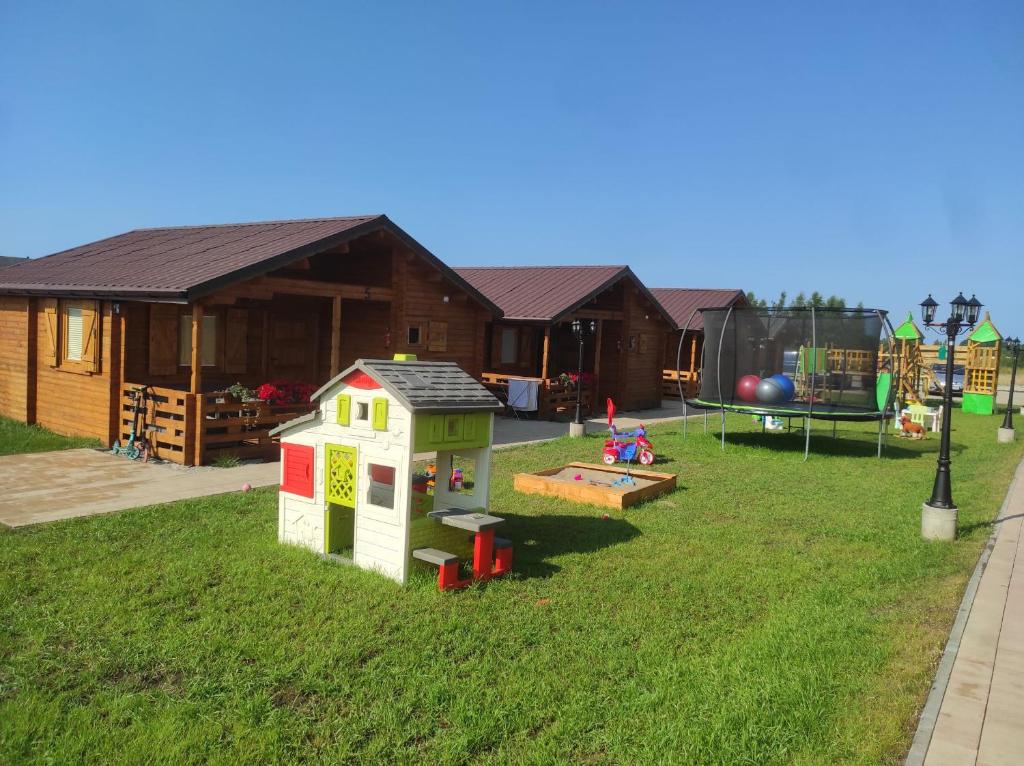 un patio de juegos con una casa de juegos y un parque infantil en Familijny Zakątek domki letniskowe Gąski en Gąski