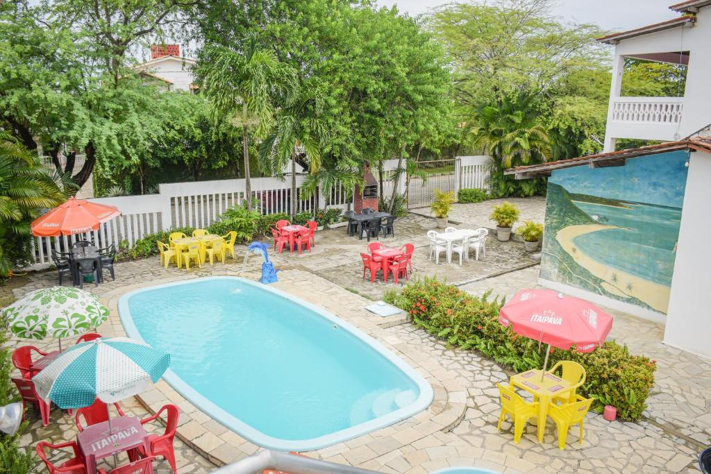 una piscina al aire libre con mesas, sillas y sombrillas en Passarela do Caranguejo PB en Conde