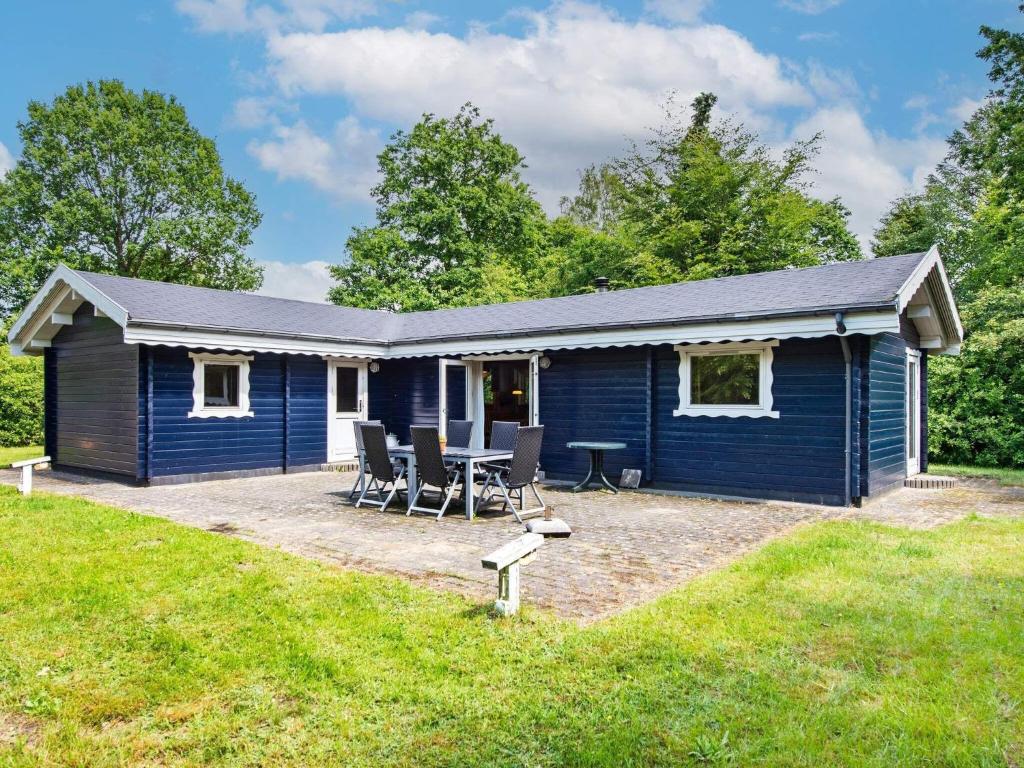 a blue cottage with a table and chairs in the yard at 6 person holiday home in Silkeborg in Silkeborg