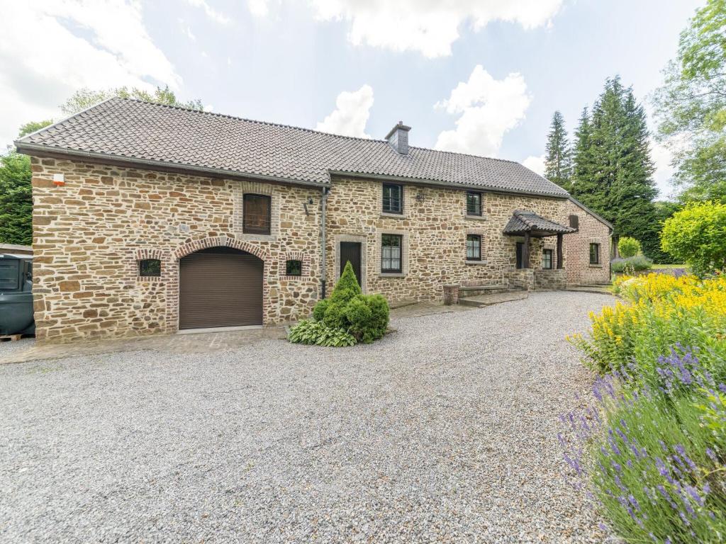 uma casa de pedra com uma garagem e uma entrada em Cosy farmhouse in Theux with private garden em Theux