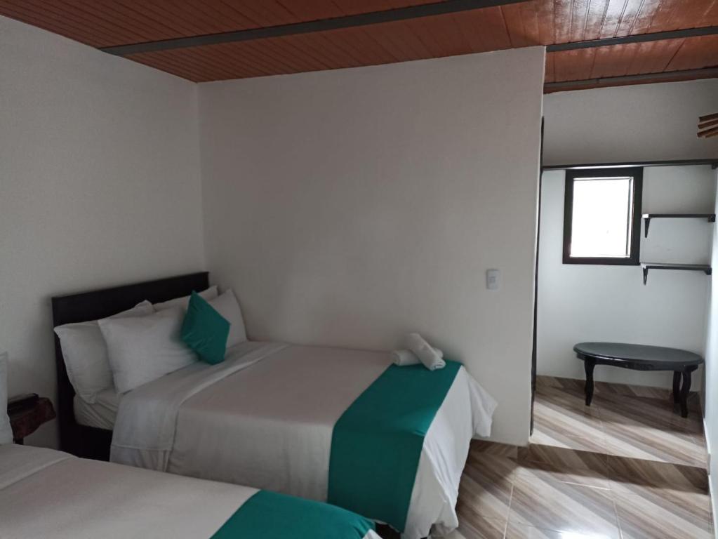 1 dormitorio con 2 camas, mesa y ventana en Hotel SAMAI en San Agustín
