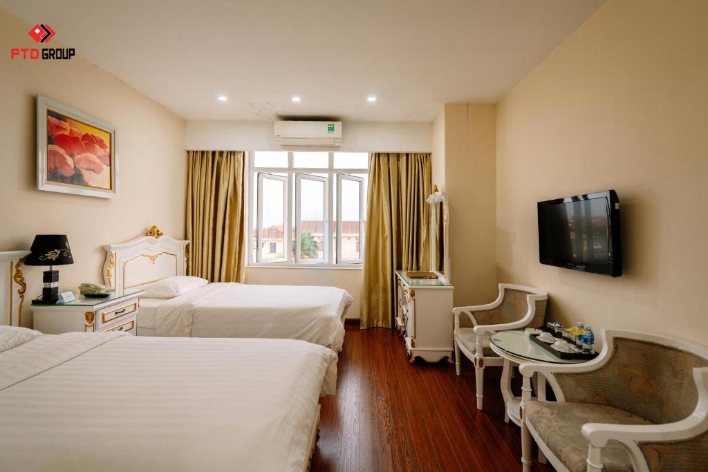a hotel room with two beds and a tv at White Hotel in Hà Tĩnh