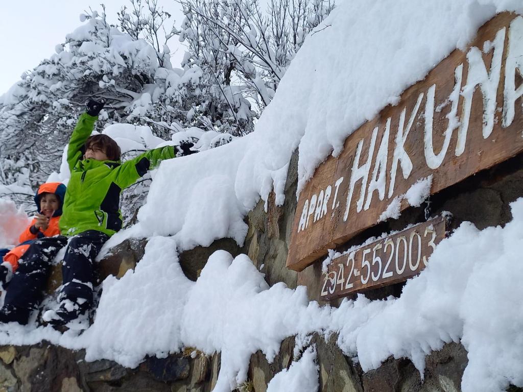 a couple of people in the snow next to a sign at Apart HAKUNA in Villa Pehuenia
